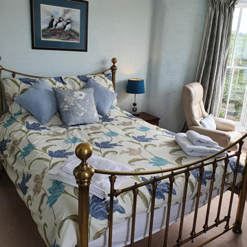 B&B in Little Haven and Wales large double bed with brass bed frame puffin painting on the wall and blue room décor