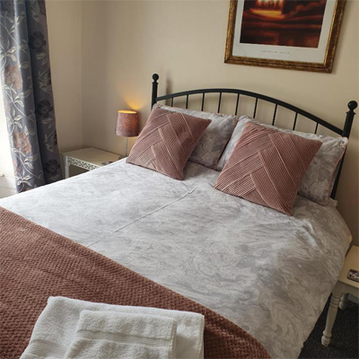 B&B in Little Haven and Wales pink and cream decorated guest room with pink pillows and wall hung picture above the bed